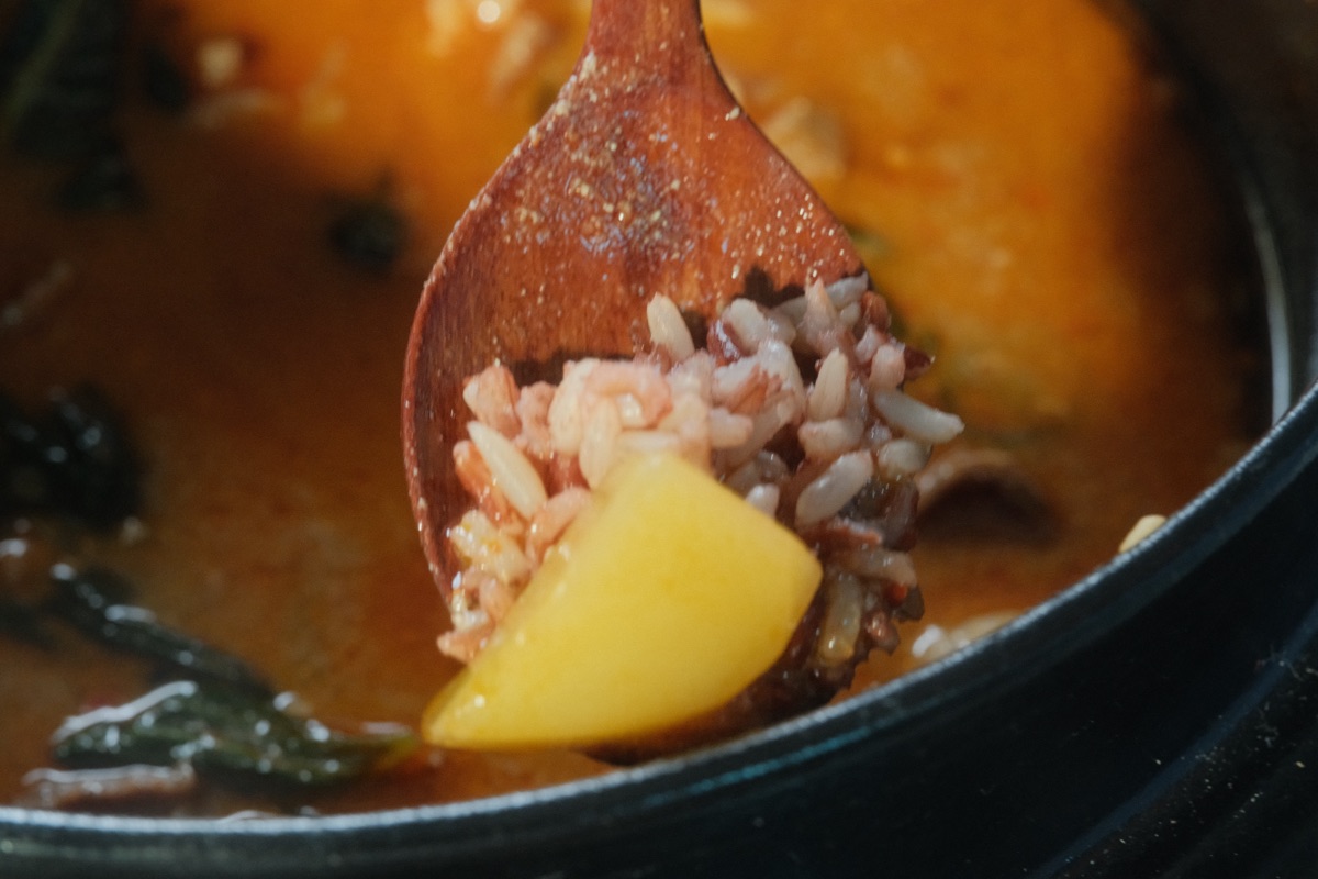 Wooden spoon with rice and potato chunk in gamjatang broth