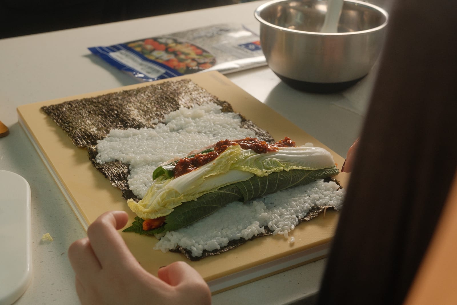 Bossam gimbap filling layered on rice and seaweed before rolling