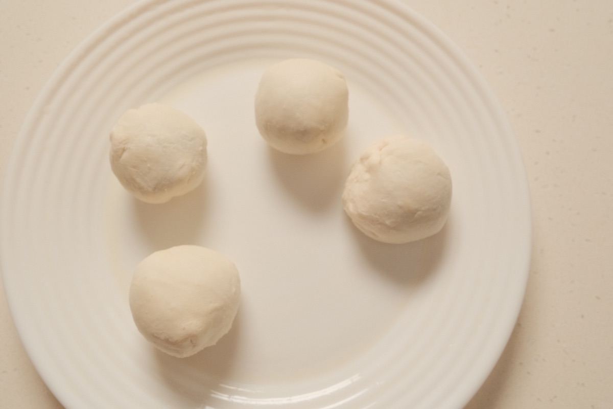Four sealed paratha dough balls ready for frying