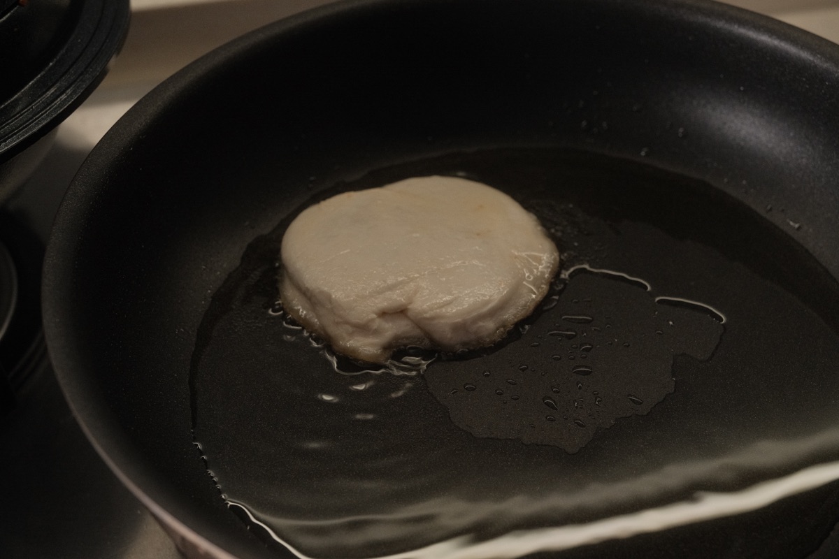 A freshly shaped paratha hotteok beginning to fry seam-side down