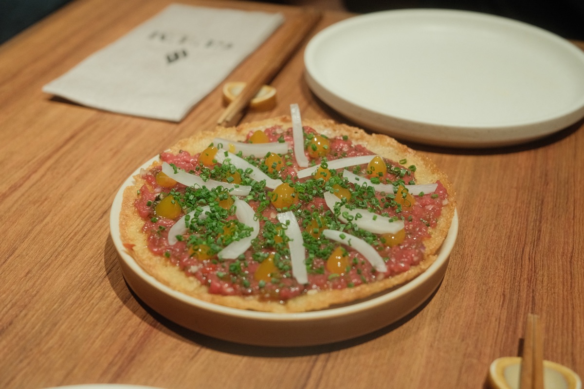 Whole Yukhwae Jeon topped with yukhoe, soy-braised yolk, pickled onion and chives