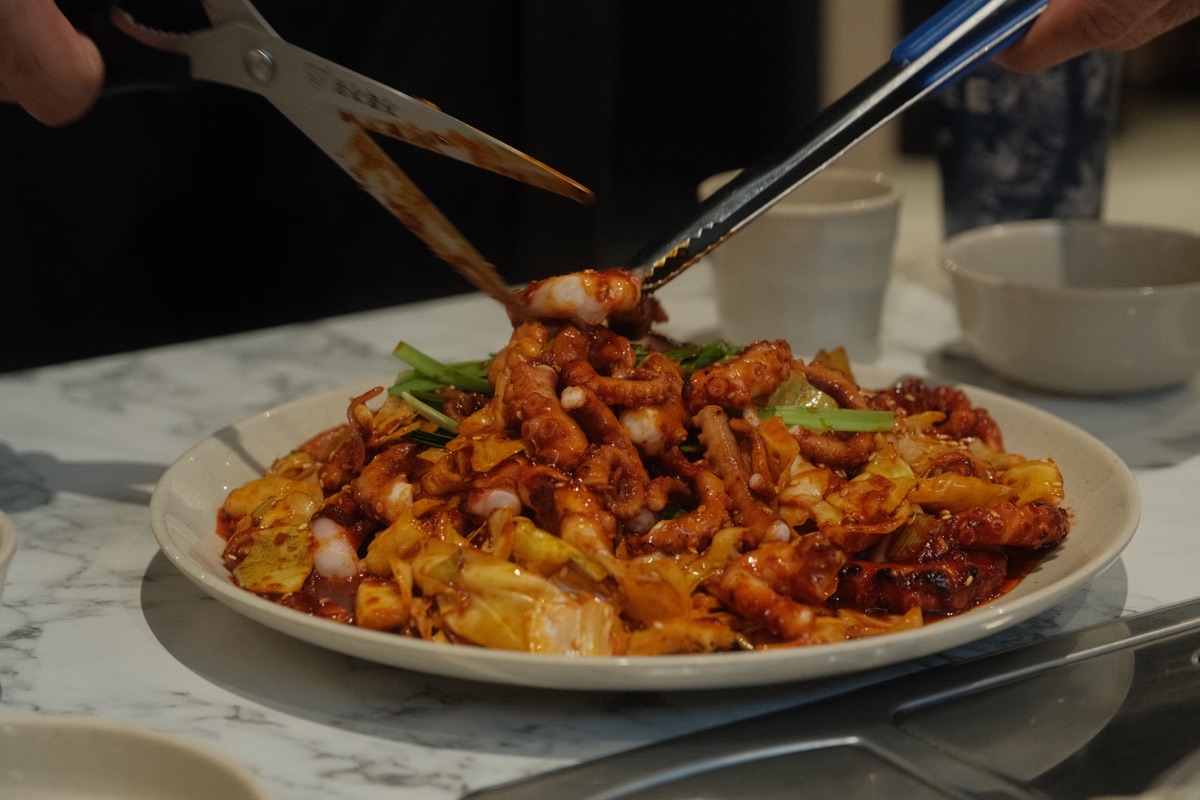 Spicy stir-fried octopus being cut with kitchen scissors